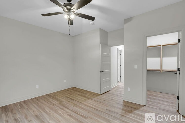 A room with a ceiling fan and light, hardwood floors, and white walls.