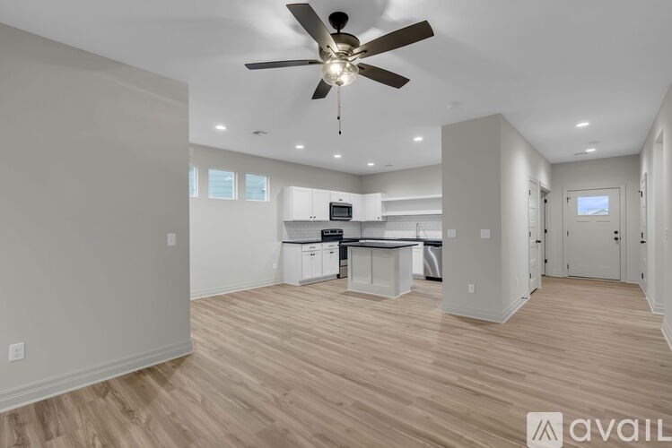 A spacious room with a ceiling fan and wooden flooring.