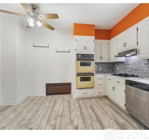 A kitchen with a fan, oven, and stove top.