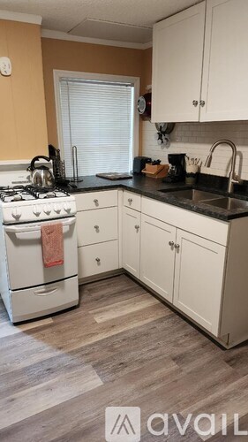 A kitchen with a white fridge and a table with two stools.