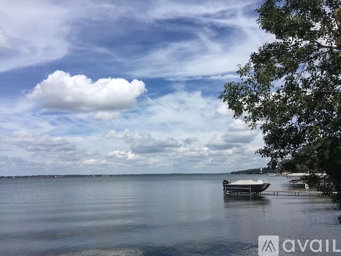 A calm lake with a boat docked on the shore and trees on the right side.