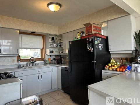 A black fridge in a kitchen with a white counter top.