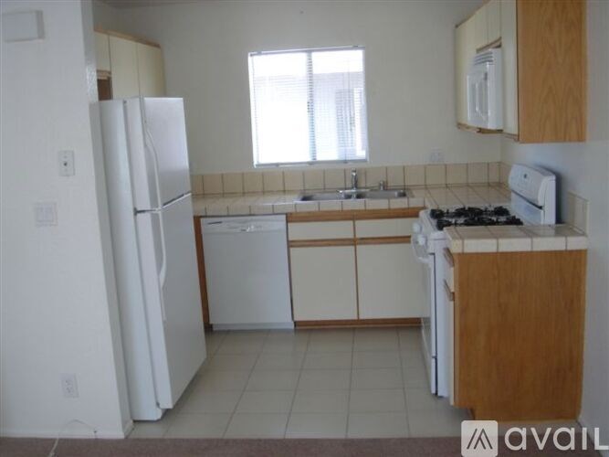 A kitchen with white appliances and wooden cabinets.
