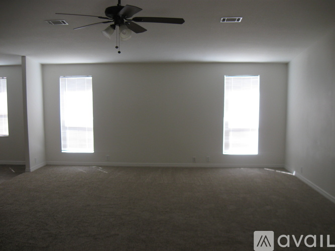A room with a ceiling fan and two windows.
