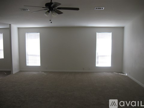 A room with a ceiling fan and two windows.