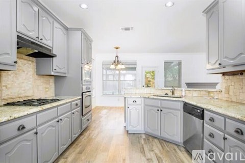 A kitchen with grey cabinets and a marble countertop.