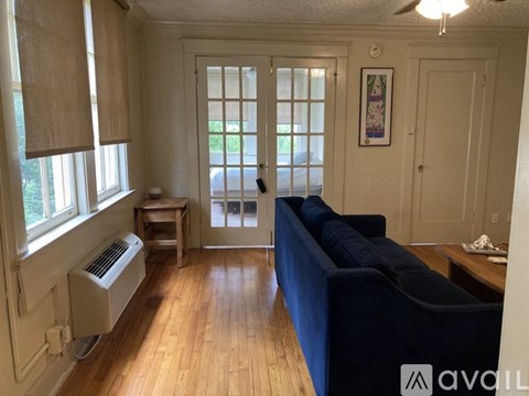 A living room with a blue couch and a window with blinds.