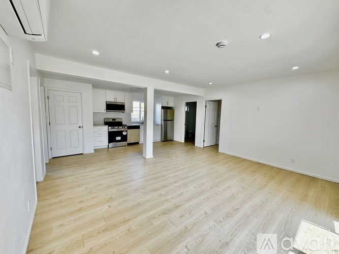 A spacious living room with wooden flooring and white walls.