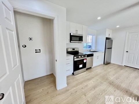 A kitchen with white cabinets and a wooden floor.