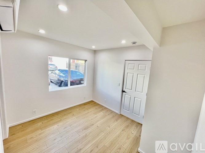 A room with wooden flooring and a white door is available for rent.