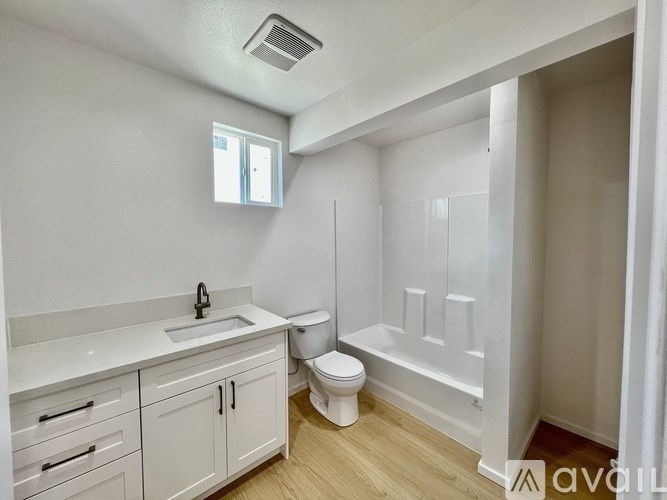 A white bathroom with a toilet, sink, and cabinetry.