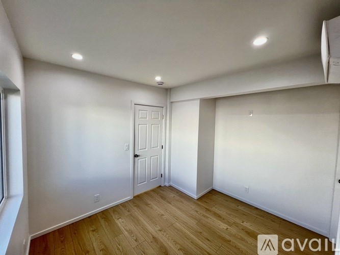 A room with wooden flooring and a white door.