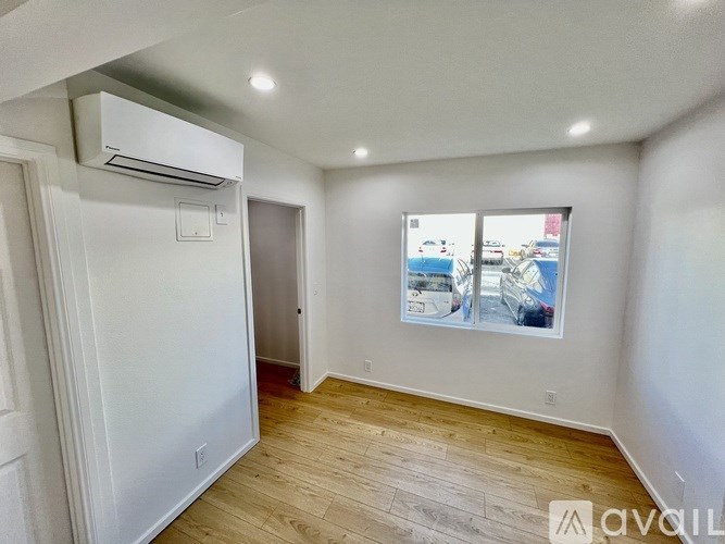 A room with a wooden floor and a wall-mounted air conditioner.
