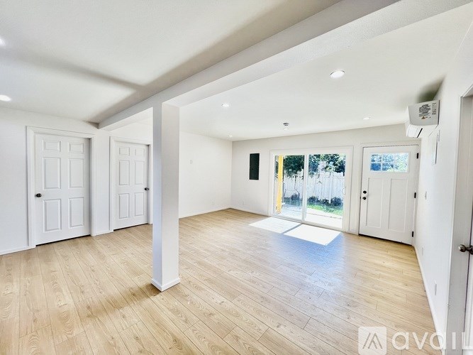 A spacious room with wooden flooring and white walls.
