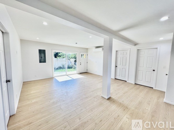 A spacious room with wooden flooring and white walls.