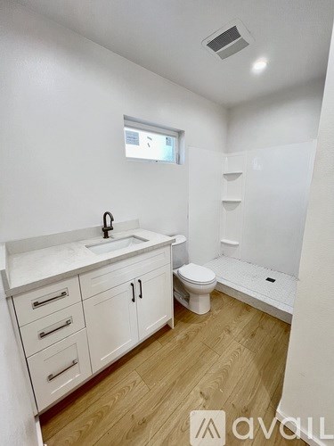 A bathroom with a sink, toilet, and a window.