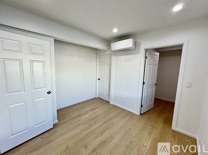 A room with a white door, a white wall, and a white ceiling with a light fixture.