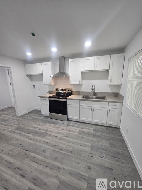 A kitchen with white cabinets and a wooden floor.