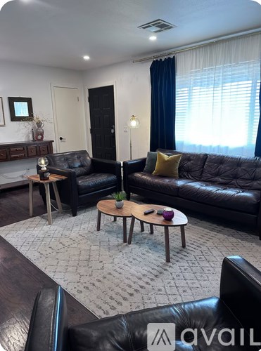 A living room with a black leather couch and a coffee table.