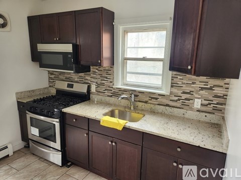 A kitchen with brown cabinets and a black stove top oven.