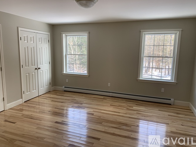 A room with wooden floors and two windows.
