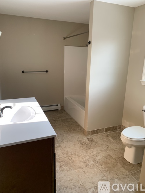A bathroom with a toilet, sink, and a shower stall.