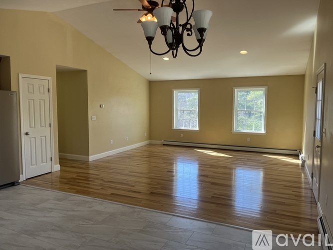 A large empty room with wooden floors and a chandelier.