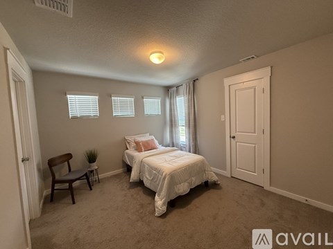 A bedroom with two beds and a chair.