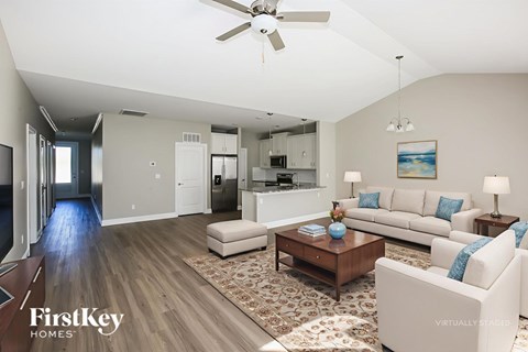 A spacious living room with a white sofa set and a wooden coffee table.