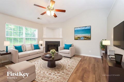 A living room with a fireplace and a painting of a beach scene on the wall.