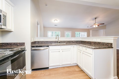 A kitchen with white cabinets and a granite countertop.