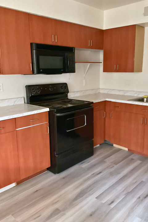 A black oven and microwave in a kitchen with wooden cabinets.