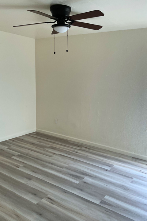 A room with a ceiling fan and wooden flooring.