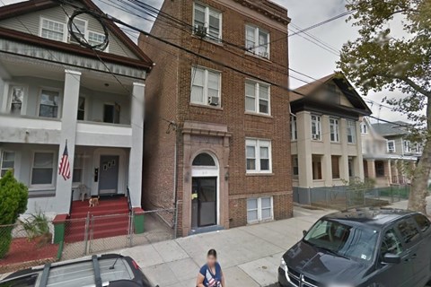 A person walks in front of a brick building with a flag on the left.