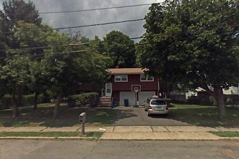 A red house with a white door and a car parked in front.