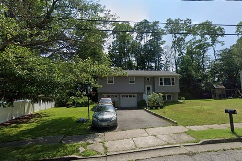 A house with a grey car parked in front.