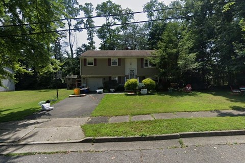 A house with a driveway and trees in the background.