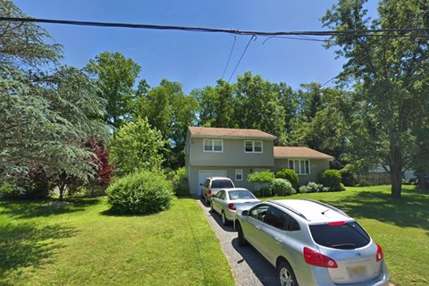 A silver car is parked in front of a house.