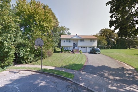 A residential street with a house and a parked car.