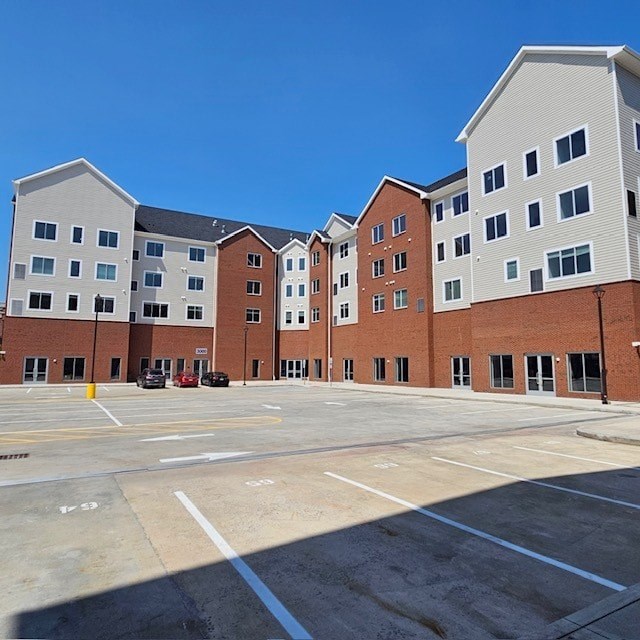 A parking lot in front of a multi-story brick building.