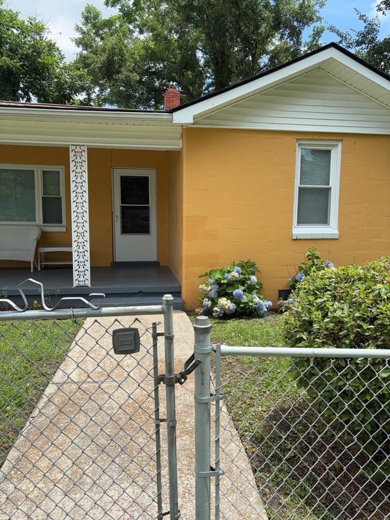 A yellow house with a white door and a grey fence.