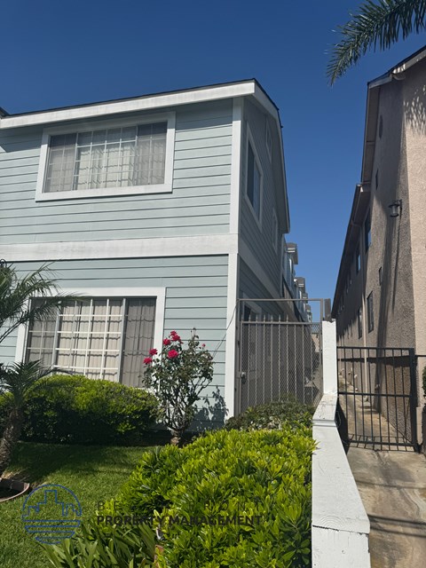 A blue house with a white fence and a gate.