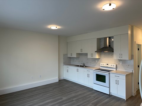 A kitchen with white cabinets and a stove top oven.