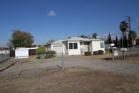 A house with a white garage door is surrounded by a fence.