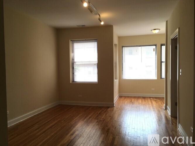 A room with wooden floors and two windows.