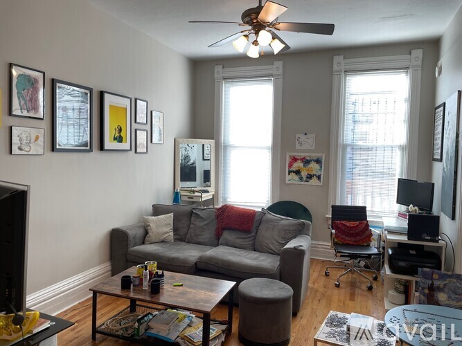 A living room with a grey couch, a coffee table, a television, and a ceiling fan.