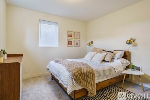 A bedroom with a bed, a nightstand, and a small table.