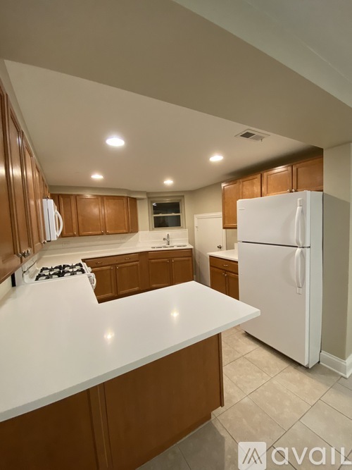 A kitchen with white appliances and brown cabinets.