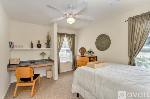 A bedroom with a bed, desk, chair, and window.