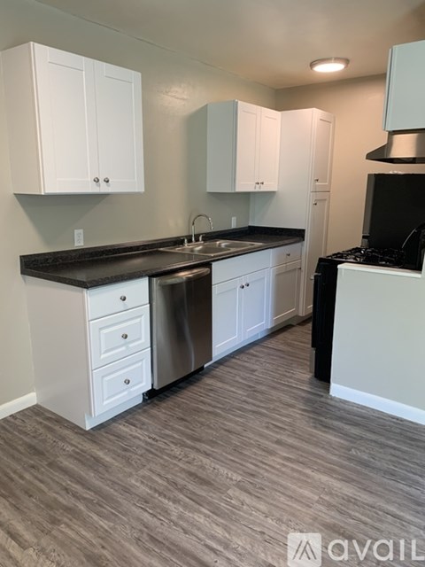 A kitchen with white cabinets and a black countertop.